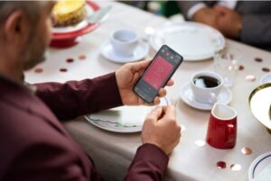 A man using the ReSound app on his phone at the table